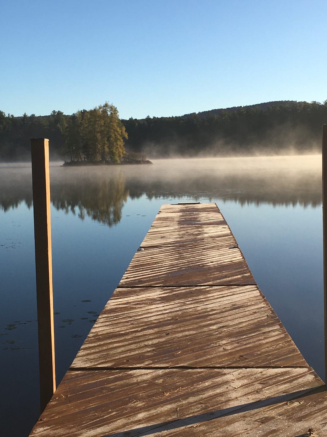Dock stretching into a mist-covered lake at sunrise