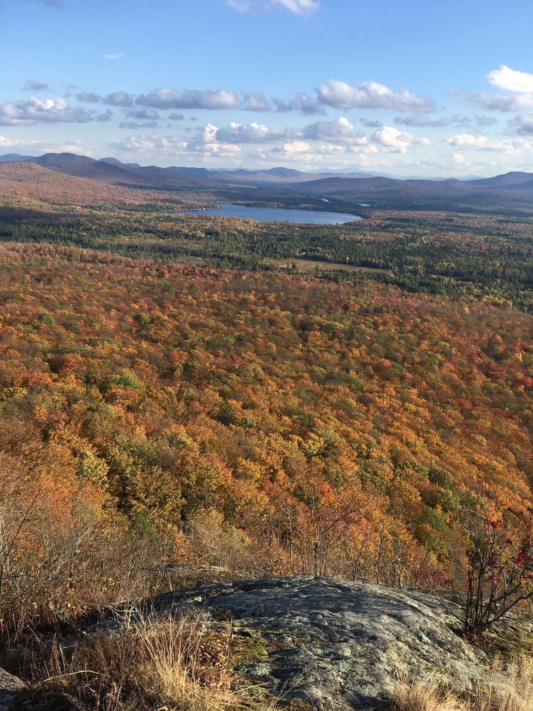 Autumn foliage rolling down to a lake in the Adirondack hills